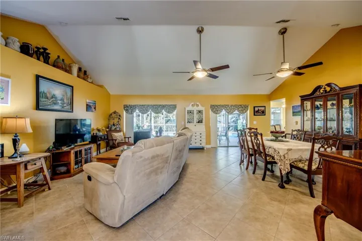 Tiled living room with ceiling fan and lofted ceiling