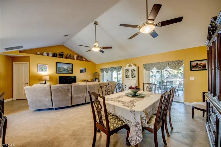 Dining space with ceiling fan, light tile patterned floors, and vaulted ceiling