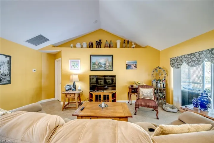 Living room with light tile patterned floors and vaulted ceiling