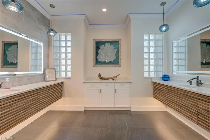 Full bath with two vanities, crown molding, dark tile patterned floors, and recessed lighting