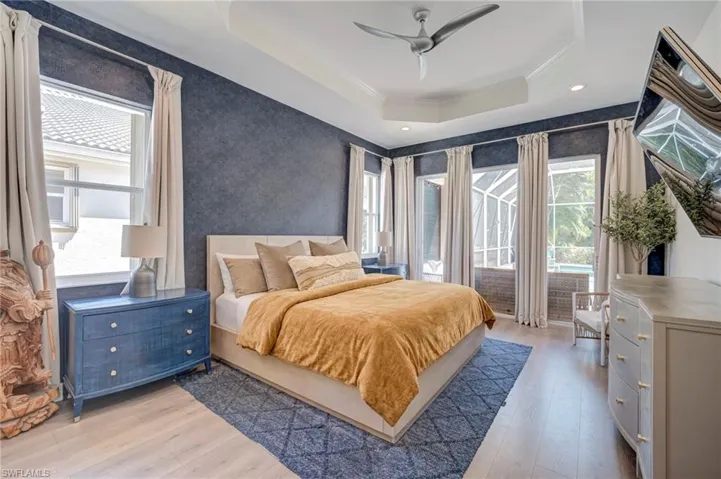 Bedroom featuring access to outside, light wood-style floors, ceiling fan, multiple windows, and ornamental molding