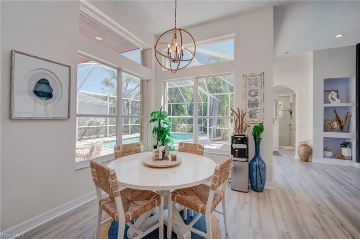Dining area with arched walkways, light wood-style flooring, hanging lights, and built in shelves