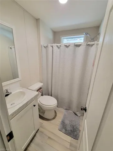 Full bath with curtained shower, vanity, and light wood-style flooring