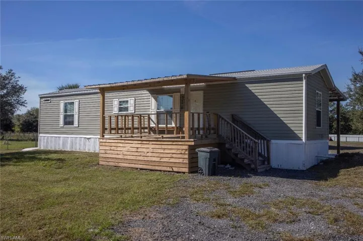 View of front facade with a front lawn, a wooden deck, and stairway
