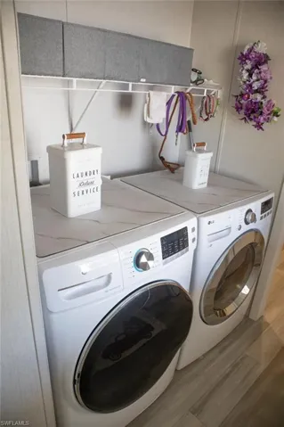 Laundry area with wood finished floors and separate washer and dryer