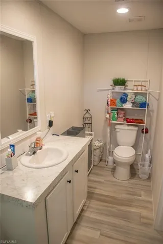 Half bathroom featuring vanity, light wood finished floors, and recessed lighting