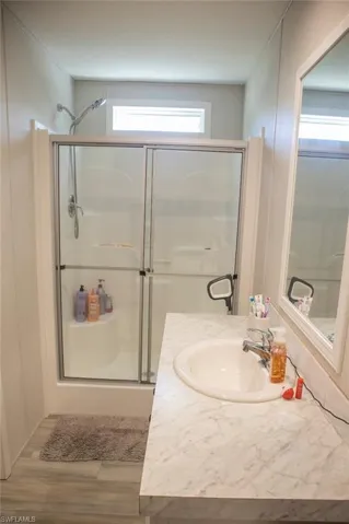 Full bathroom with a shower stall, vanity, and light wood-style flooring