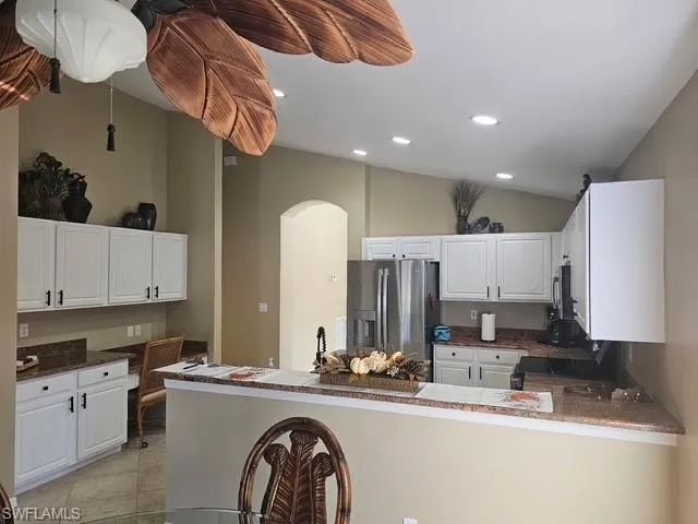 Kitchen with appliances with stainless steel finishes, recessed lighting, white cabinetry, a peninsula, and lofted ceiling