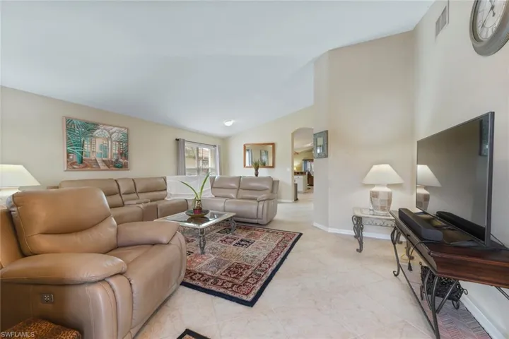 Living area featuring arched walkways, high vaulted ceiling, and light tile patterned flooring