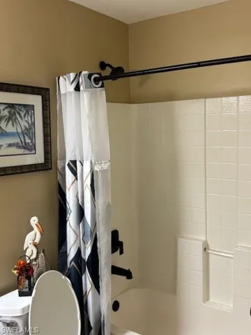 Full bath featuring shower / tub combo with curtain and toilet