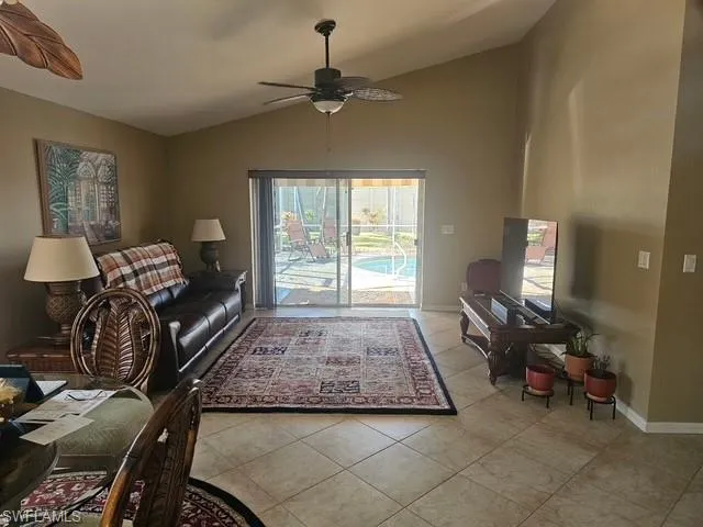 Living area featuring lofted ceiling, light tile patterned flooring, and a ceiling fan