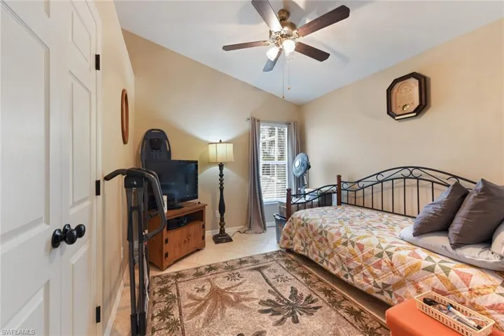 Bedroom featuring light tile patterned floors, vaulted ceiling, and a ceiling fan