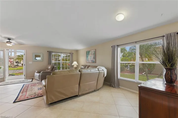 Living area with plenty of natural light, light tile patterned floors, and ceiling fan