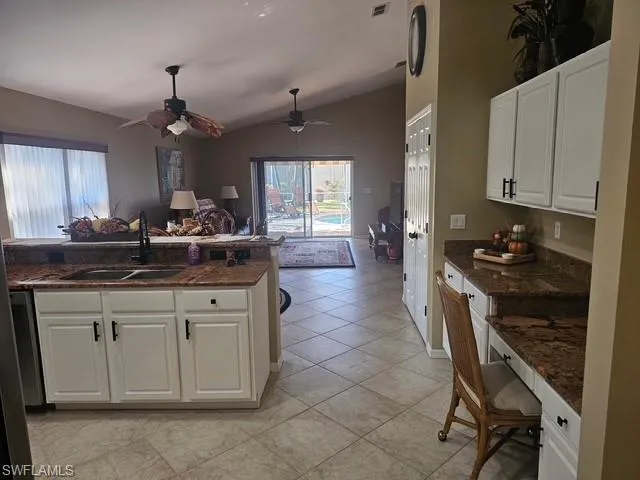 Kitchen featuring white cabinetry, open floor plan, lofted ceiling, a breakfast bar, and ceiling fan