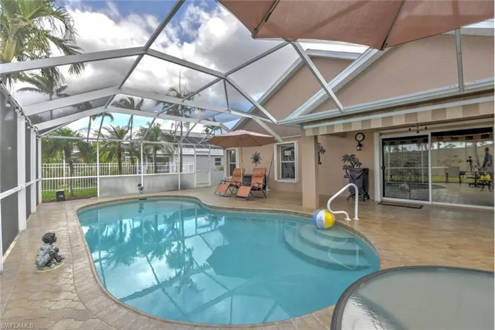 Swimming pool featuring a sunroom, a patio area, and glass enclosure