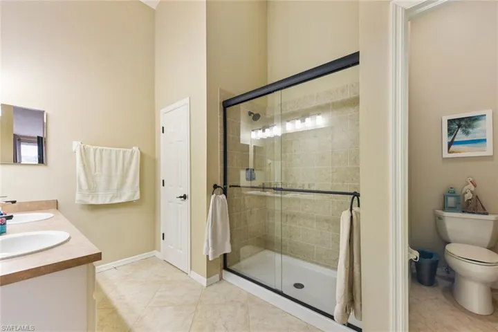 Bathroom with double vanity, a shower stall, and light tile patterned flooring