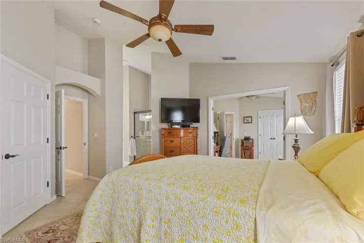 Bedroom featuring vaulted ceiling, light tile patterned floors, a ceiling fan, a closet, and arched walkways