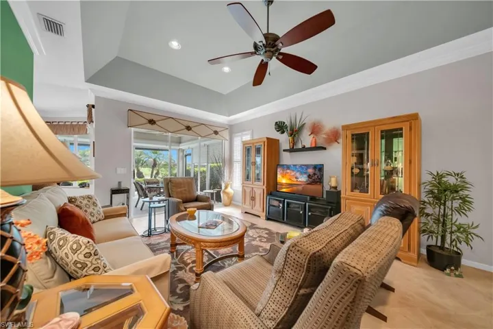 Living area with ornamental molding, ceiling fan, a tray ceiling, light carpet, and recessed lighting