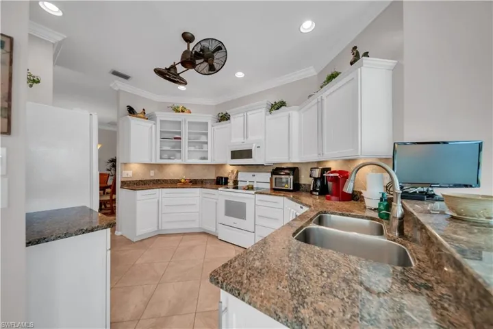 Kitchen with white cabinetry, glass fronted cabinets, white appliances, ornamental molding, and recessed lighting
