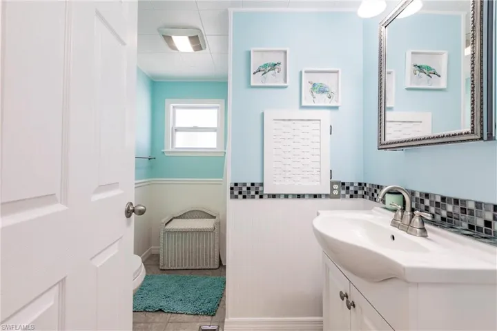Bathroom featuring tile patterned floors, a wainscoted wall, vanity, and toilet