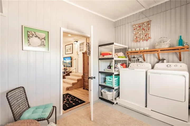 Laundry room featuring wood walls, washer and dryer, laundry area, and carpet flooring