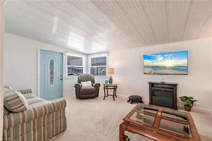 Carpeted living room featuring baseboards and wood ceiling