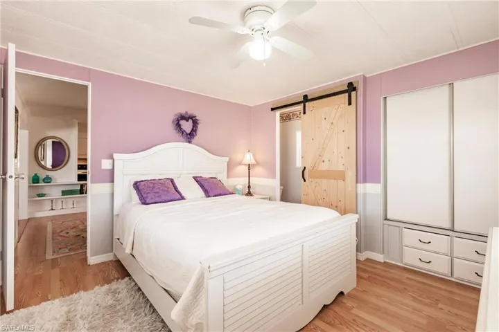 Bedroom with a barn door, baseboards, a ceiling fan, and light wood-style flooring