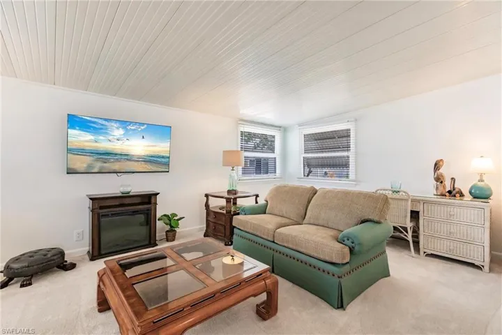 Living area featuring baseboards, carpet, and wooden ceiling