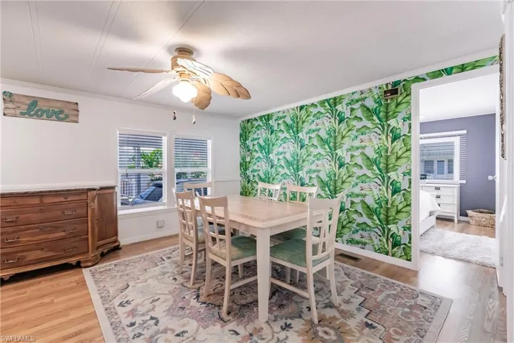 Dining room with wainscoting, visible vents, light wood-style floors, ceiling fan, and ornamental molding