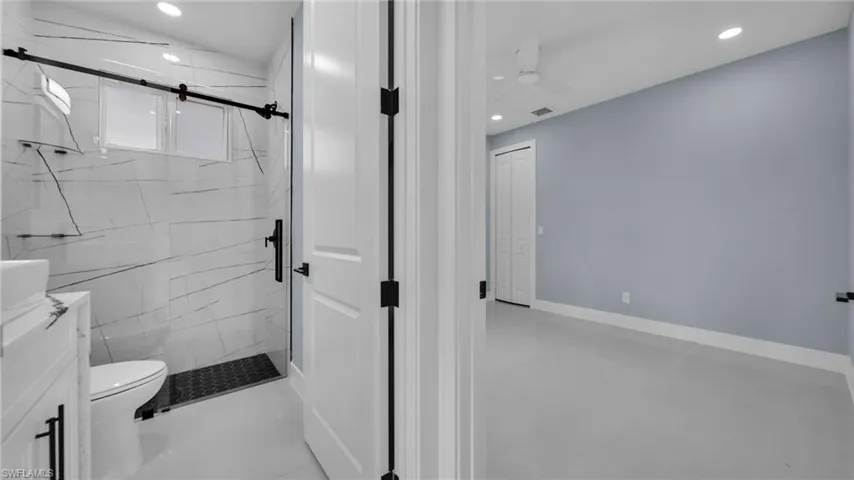 Bathroom featuring a marble finish shower, vanity, and recessed lighting