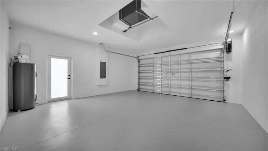 Garage with water heater, recessed lighting, a garage door opener, and electric panel
