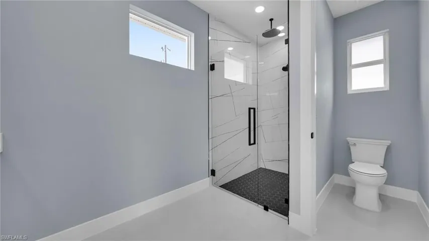 Bathroom featuring a marble finish shower and healthy amount of natural light