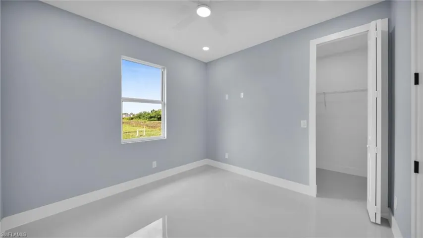 Unfurnished bedroom featuring a ceiling fan, recessed lighting, finished concrete floors, and a walk in closet