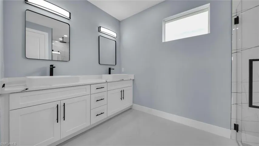 Full bath with double vanity and a shower with door