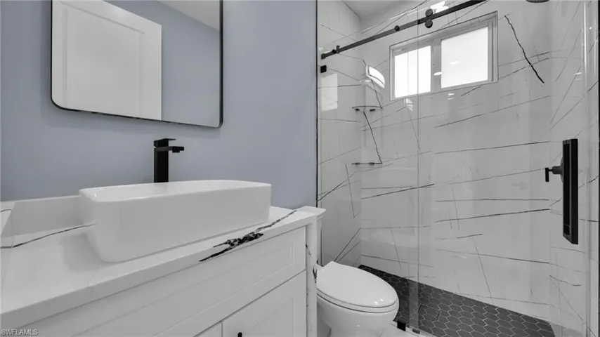 Bathroom featuring vanity and a marble finish shower