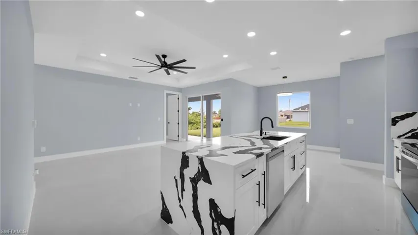 Kitchen featuring a raised ceiling, recessed lighting, white cabinets, ceiling fan, and stainless steel appliances
