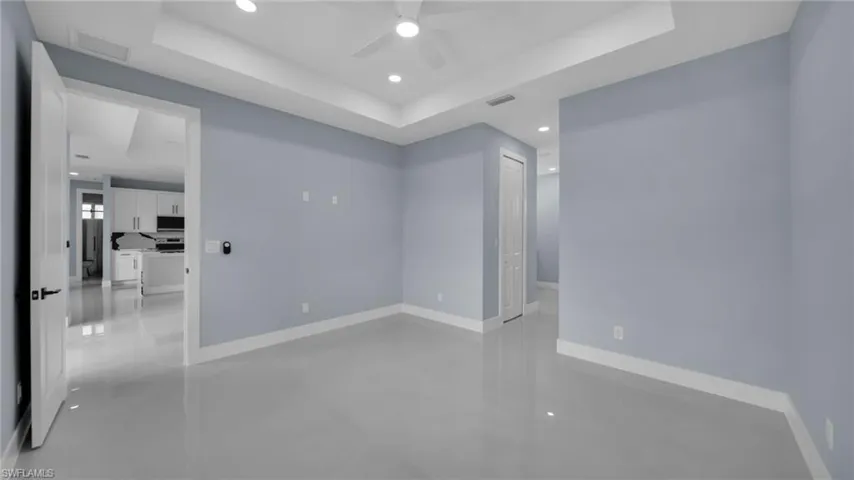 Spare room with a tray ceiling, a ceiling fan, recessed lighting, and finished concrete floors