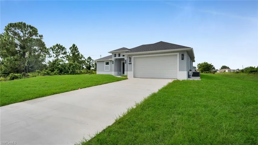 Prairie-style house featuring a garage, a front yard, concrete driveway, stucco siding, and roof with shingles