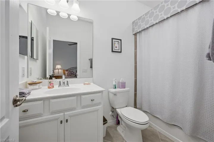Ensuite bathroom featuring vanity, shower / bath combo with shower curtain, and light tile patterned floors