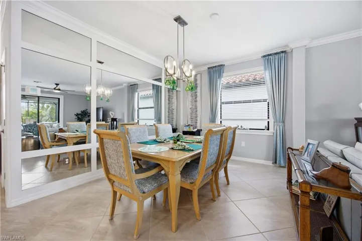 Dining room with suspended lighting, crown molding, a ceiling fan, and light tile patterned floors