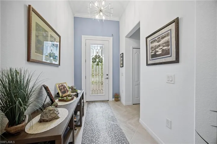 Foyer entrance with hanging lights and ornamental molding