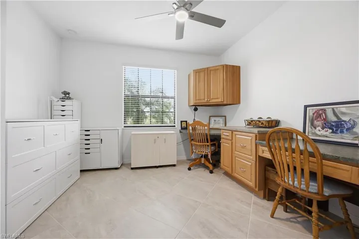Office space featuring built in desk, a ceiling fan, and light tile patterned floors