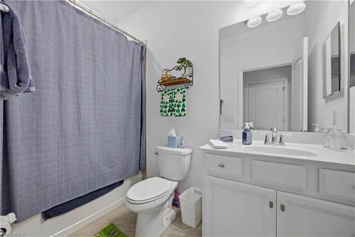 Bathroom with vanity, shower / bath combo, and light tile patterned flooring