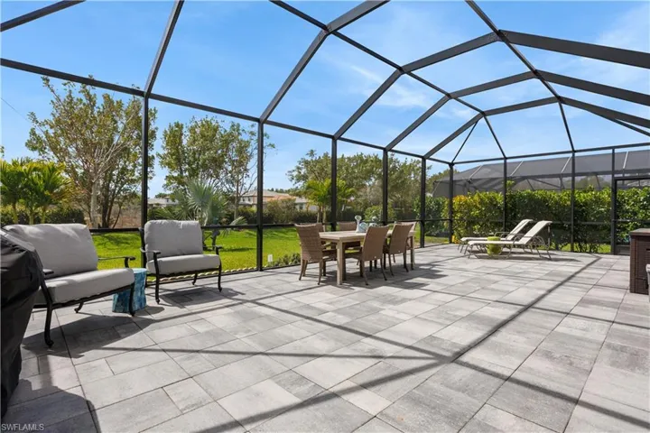 View of patio featuring a sunroom, outdoor dining area, and glass enclosure