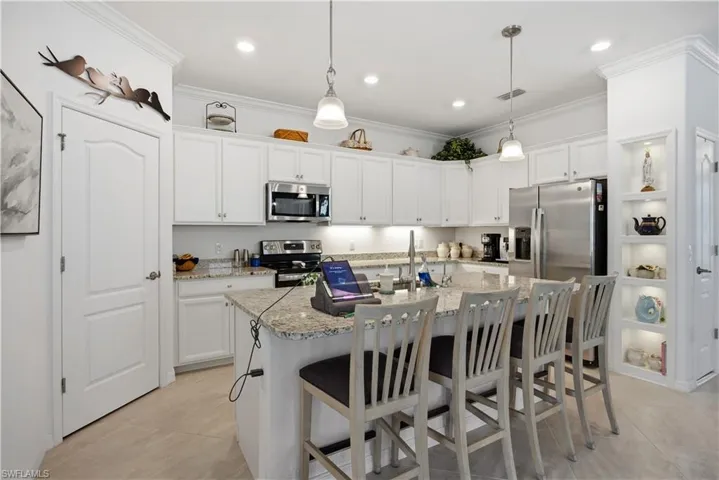 Kitchen with white cabinets, a kitchen island with sink, a kitchen breakfast bar, and ornamental molding