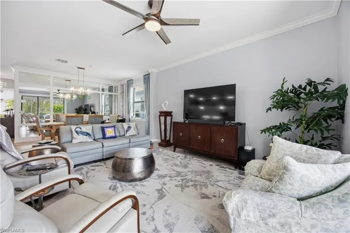Living room with crown molding, ceiling fan, and a chandelier