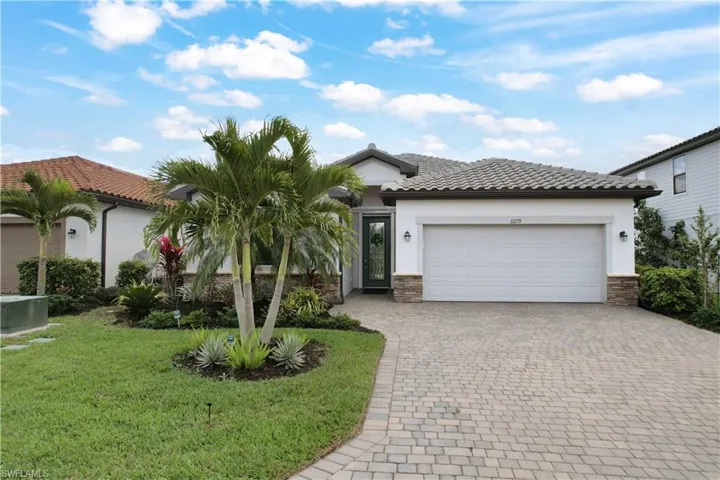 Mediterranean / spanish home featuring a garage, stucco siding, decorative driveway, a tile roof, and a front yard