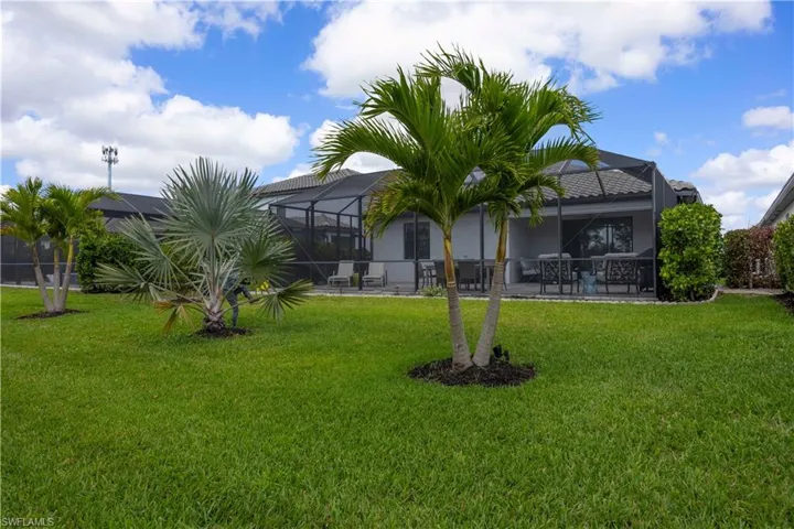 Rear view of property featuring a sunroom, a lanai, a patio, and a yard
