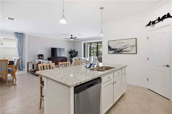 Kitchen with a breakfast bar area, open floor plan, white cabinets, decorative light fixtures, and ornamental molding