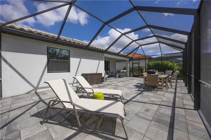 View of patio with a sunroom, outdoor dining area, and glass enclosure
